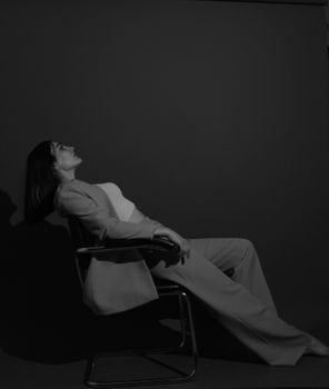Elegant woman in a black and white portrait, sitting with shadows cast behind.