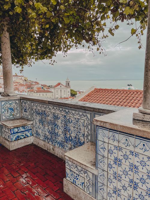 Gratis Vista incantevole di Lisbona, Portogallo, con vista sui tetti di tegole rosse e sul mare da una terrazza decorata con piastrelle. Foto a disposizione
