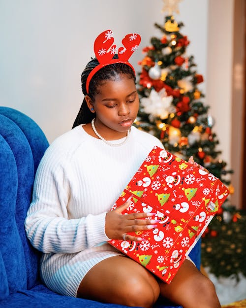 Girl with Hairband with Antlers Sitting and Holding Christmas Gift