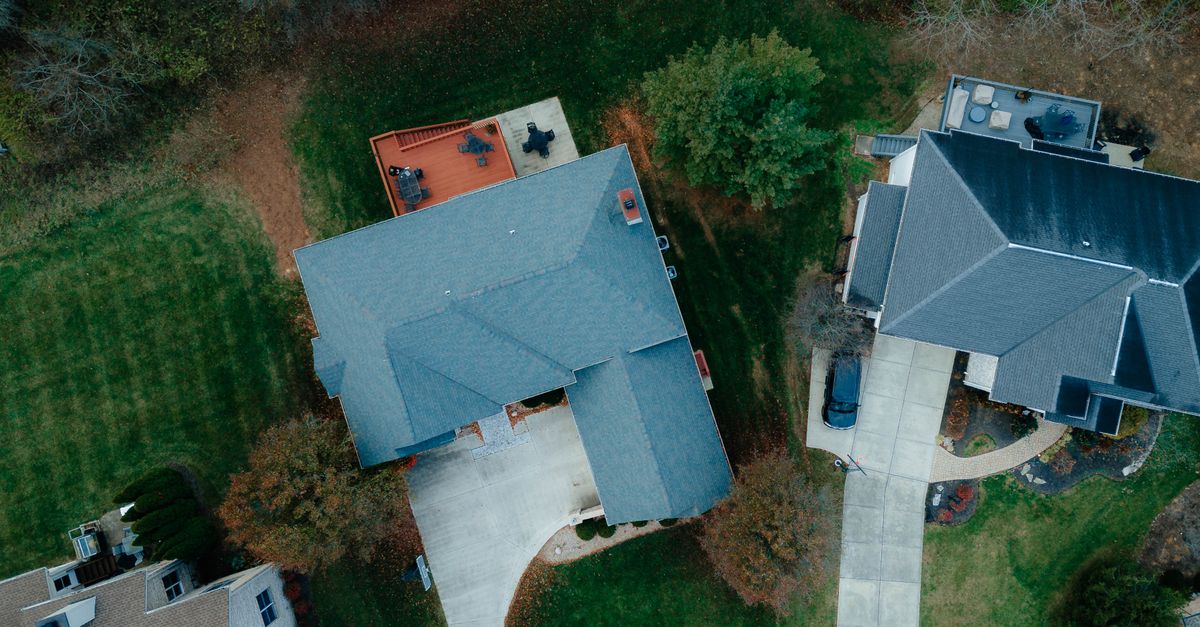 Drone shot of suburban houses with roofs and gardens, showcasing rural living from above.