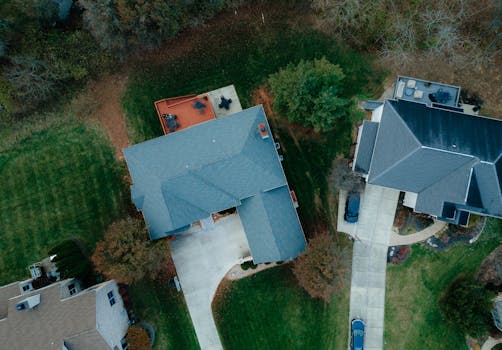 Drone shot of suburban houses with roofs and gardens, showcasing rural living from above.