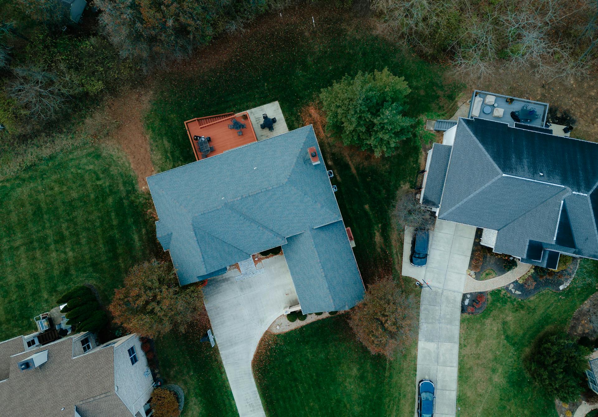 Drone shot of suburban houses with roofs and gardens, showcasing rural living from above.