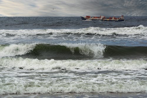 Transportation Ship behind Waves on Sea Shore