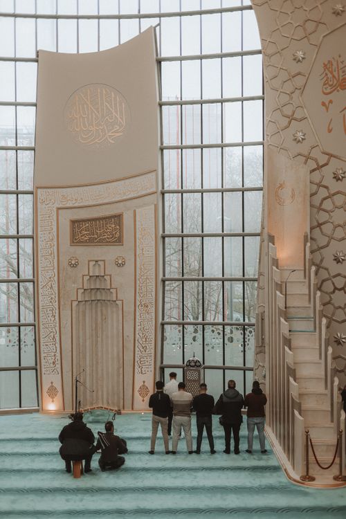 Free Interior view of the central mosque in Cologne with people praying, showcasing intricate Islamic architecture. Stock Photo