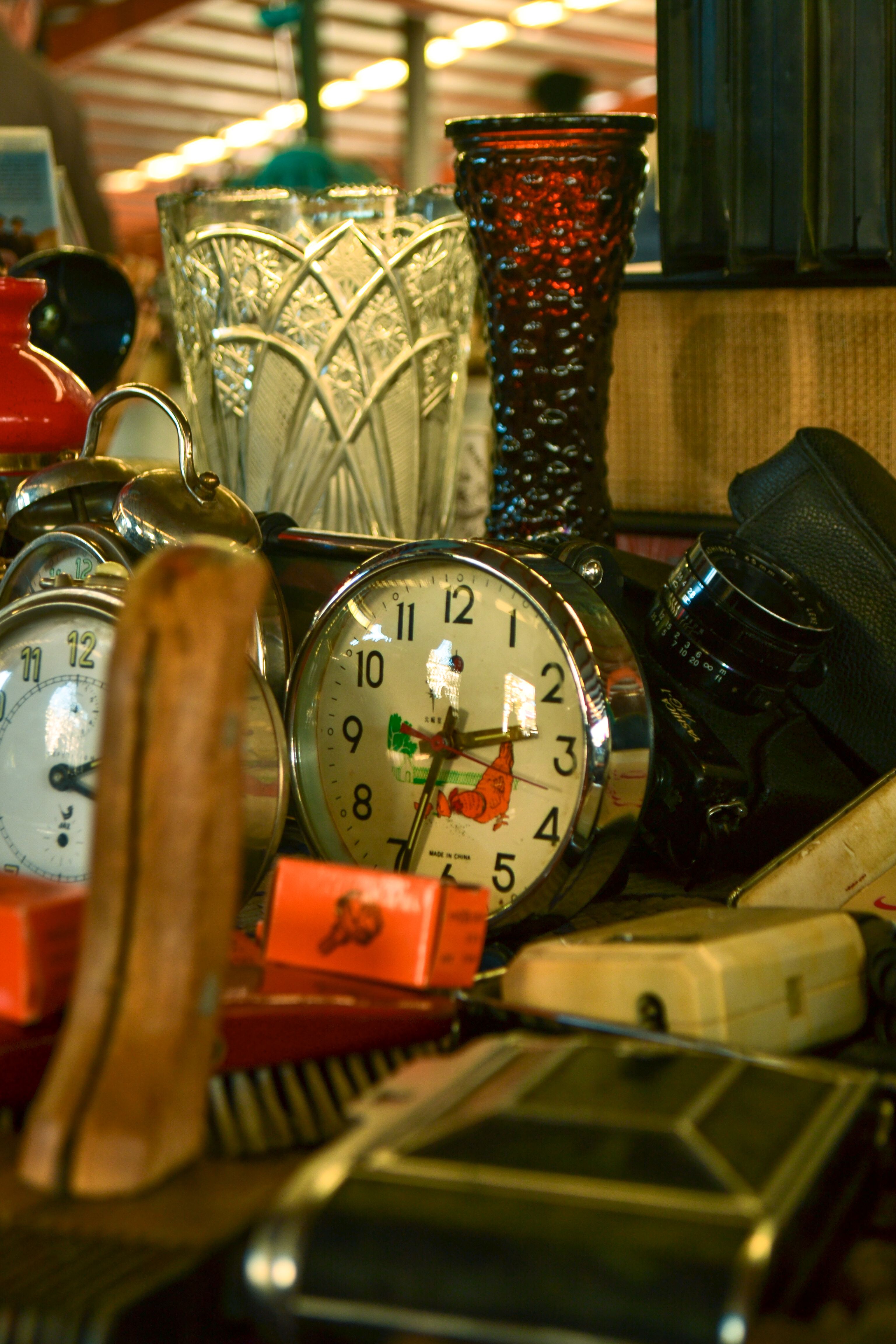 A selection of vintage clocks, glassware, and other retro items arranged on a table in a classic indoor setting.