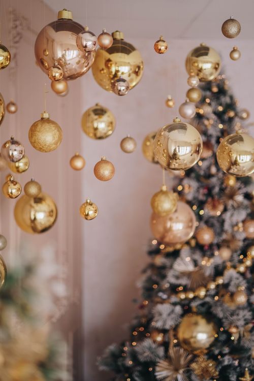 Free Luxurious golden Christmas ornaments hanging near a beautifully decorated tree. Stock Photo