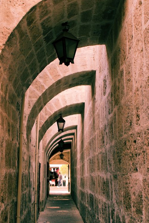 Free A narrow stone corridor in Arequipa, Peru, with vintage lamps and vaulted ceilings. Stock Photo