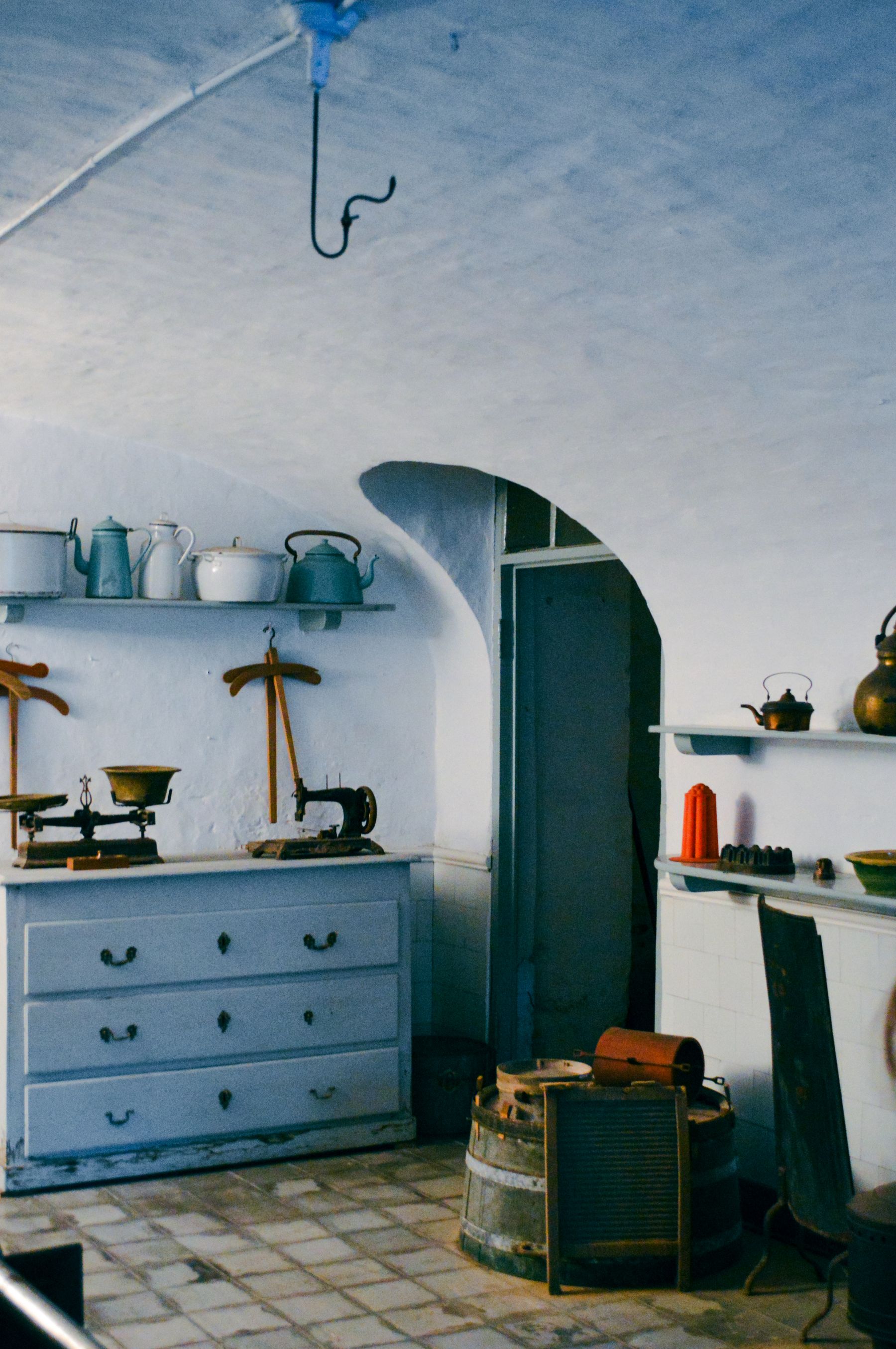 Blue-painted dresser, enamel jugs and an arched doorway in an older interior