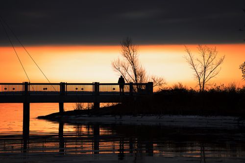 Silhouette Of Woman Standing On Dock During Sunset · Free Stock Photo
