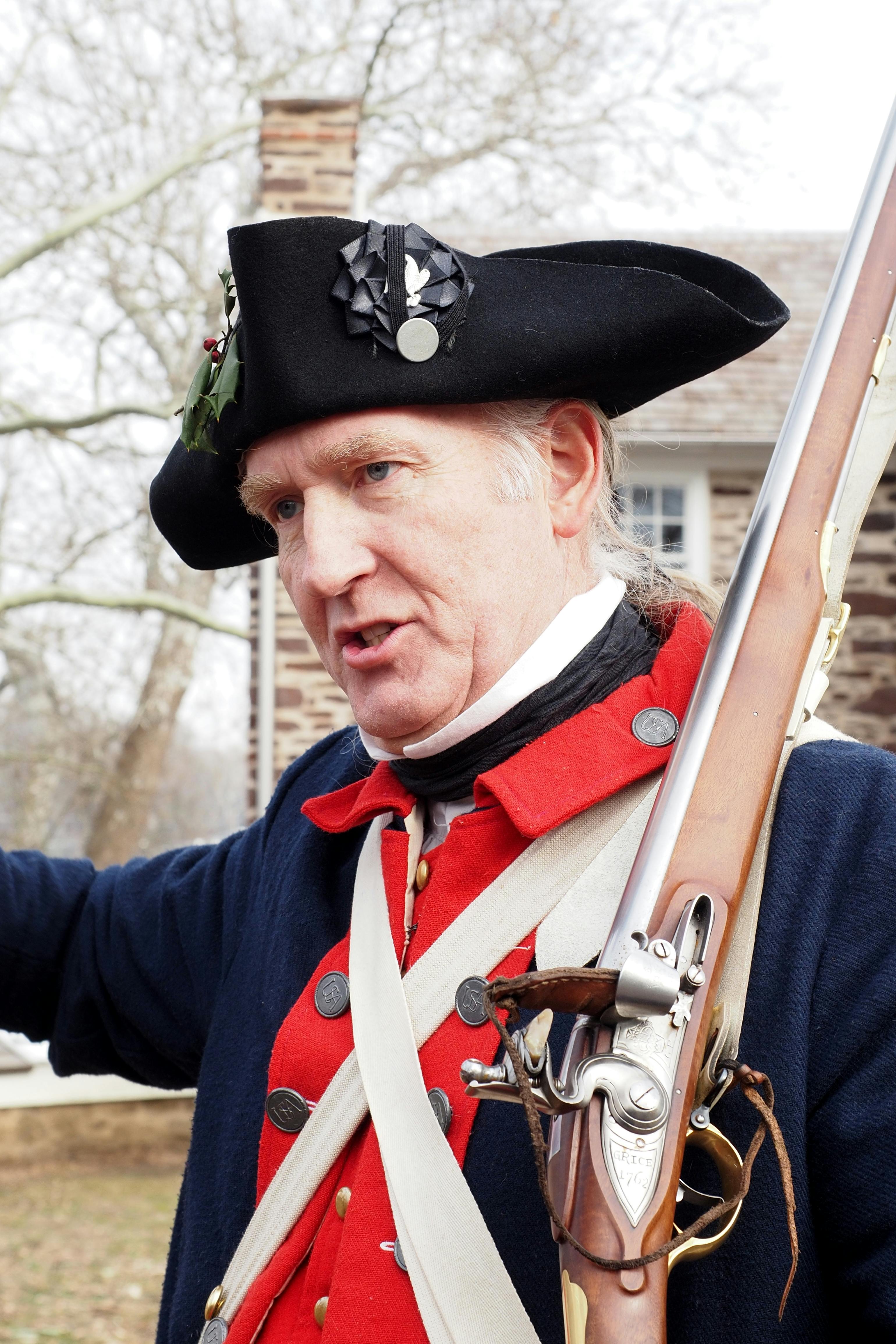 Portrait of a reenactor in vintage military uniform holding a rifle outdoors.
