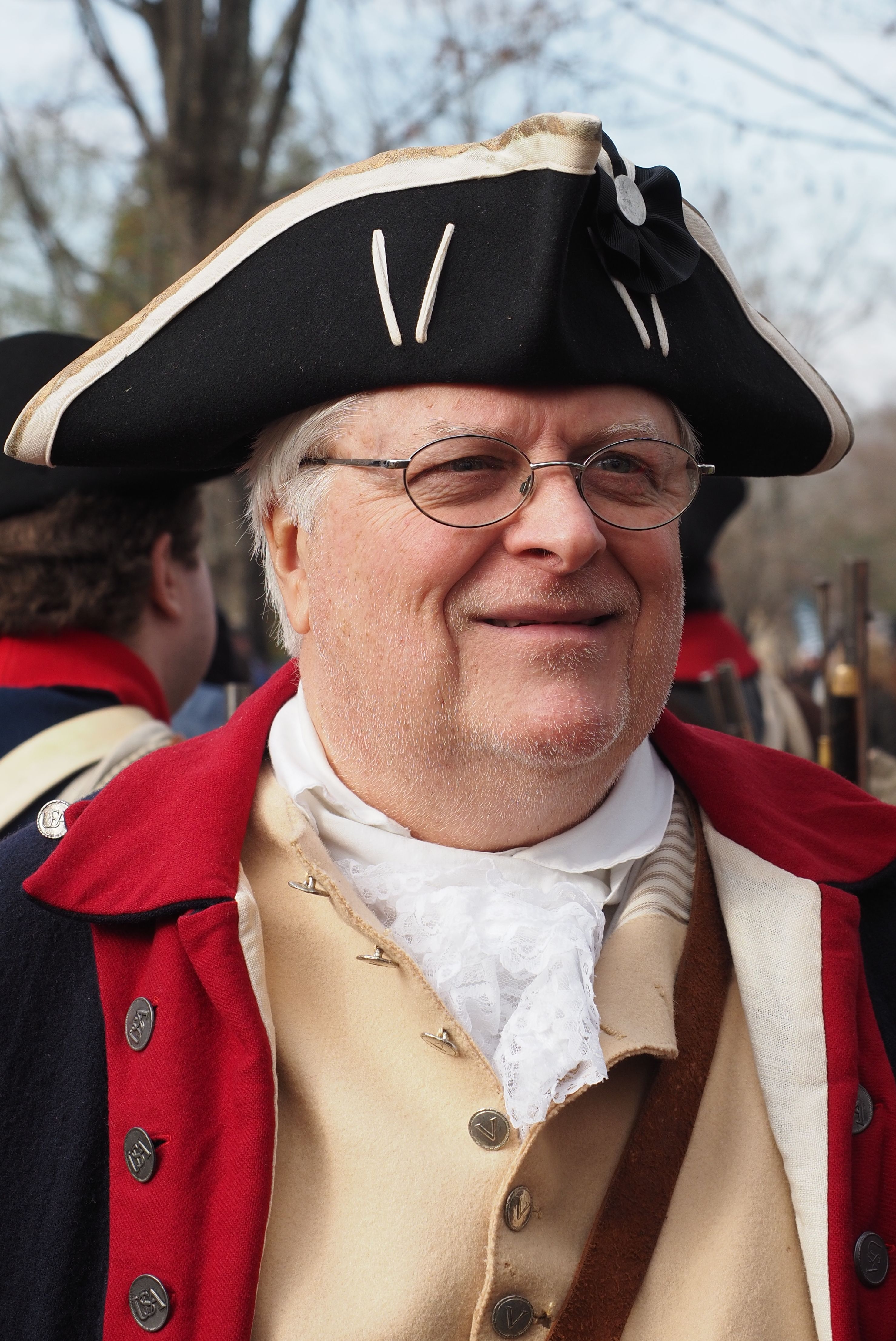 A joyful reenactor in 18th century attire participates in a historical event.