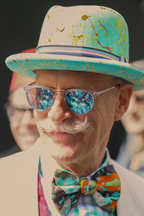 Portrait of an Elderly Man with Mustache Wearing a Colorful Hat, Sunglasses and a Bow Tie 