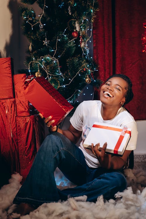 Happy Woman with Present Sitting on Floor by Christmas Tree