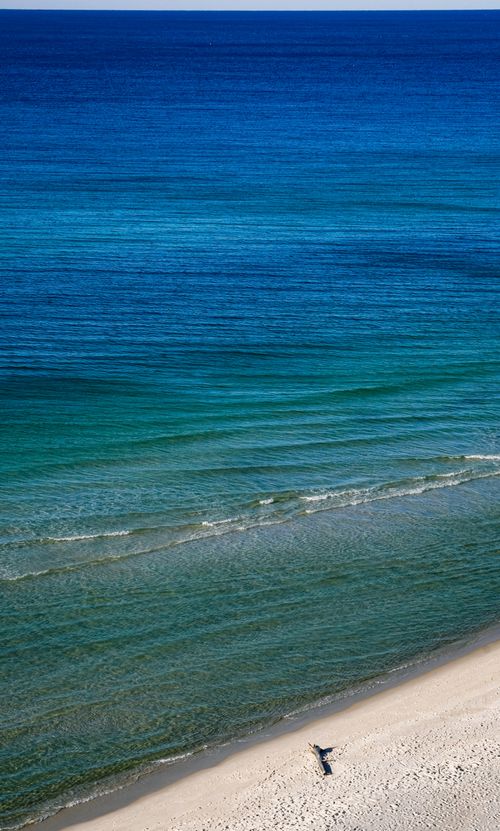 Free Tranquil beach scene with gentle waves and clear blue ocean under a bright sky. Stock Photo