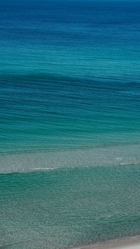 A serene view of the ocean with gentle waves in tranquil blue hues, suitable for mobile wallpaper or relaxation themes.