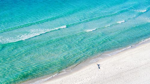 Free Aerial shot of a serene turquoise beach with gentle waves and soft sand, perfect for relaxation. Stock Photo