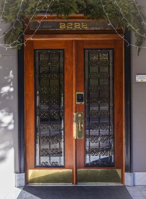 Ornate wooden double doors with lattice design and greenery, perfect for urban architectural themes.