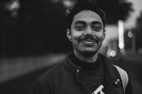 Free Black and white portrait of a smiling man outdoors with bokeh lights in the background. Stock Photo