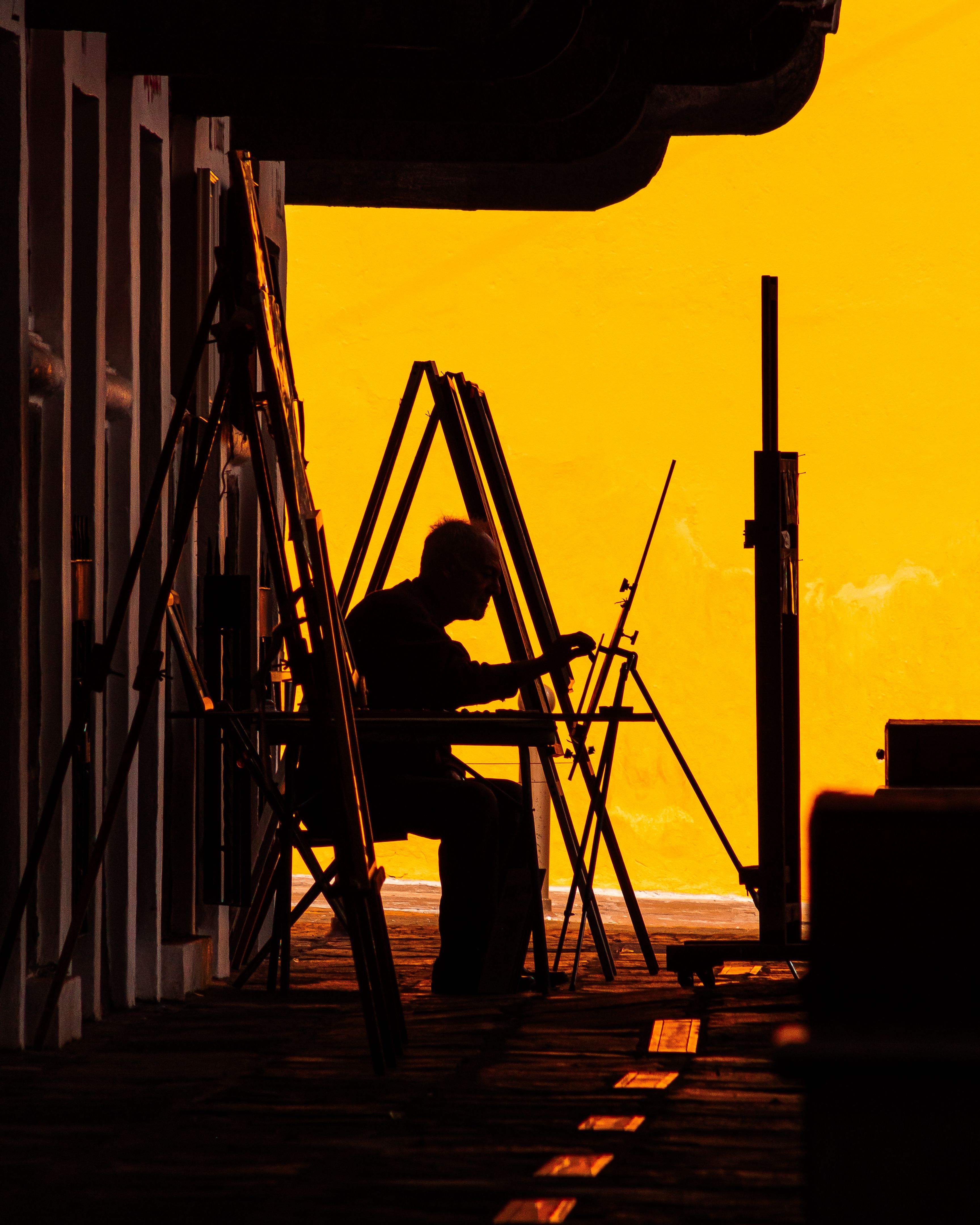 A silhouetted artist painting in a vibrant sunset scene in Heroica Puebla de Zaragoza, Mexico.