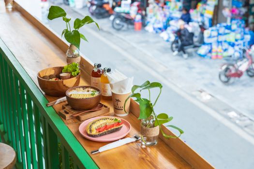 Fresh breakfast on a balcony overlooking a vibrant urban street with bustling activity below.