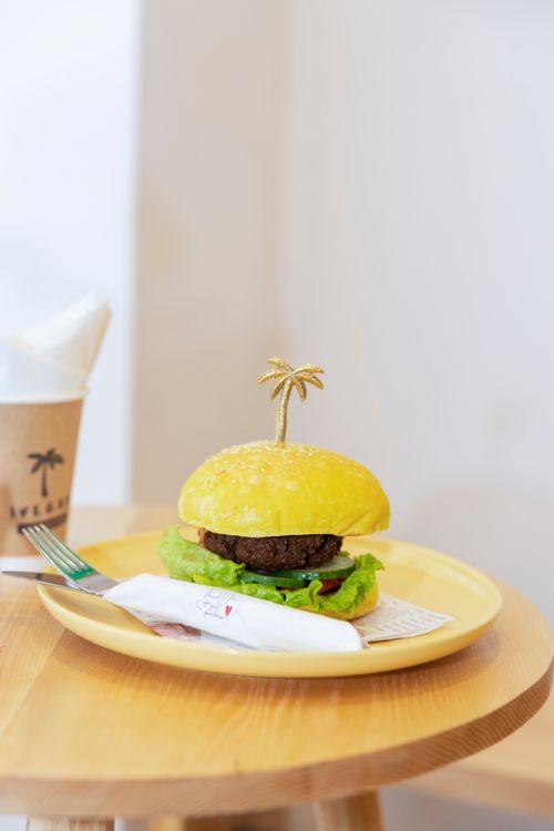 Free Elegant burger on a plate with a golden palm decoration, styled for food photography. Stock Photo