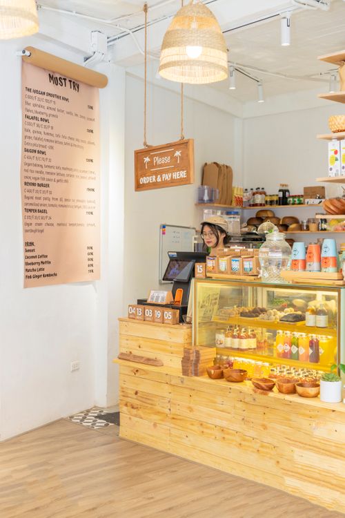 Free Warm cafe scene featuring a smiling cashier, menu board, and display case with pastries. Stock Photo
