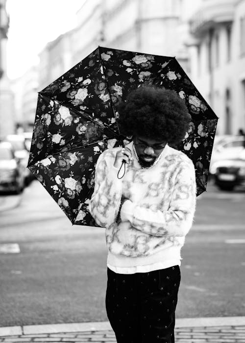A Man Standing on a Sidewalk with an Umbrella 