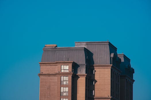 A tall architectural building framed by a clear blue sky, capturing the urban skyline.