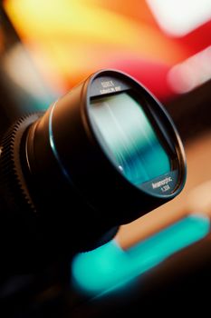 Detailed shot of an anamorphic camera lens showcasing reflections and vibrant colors.
