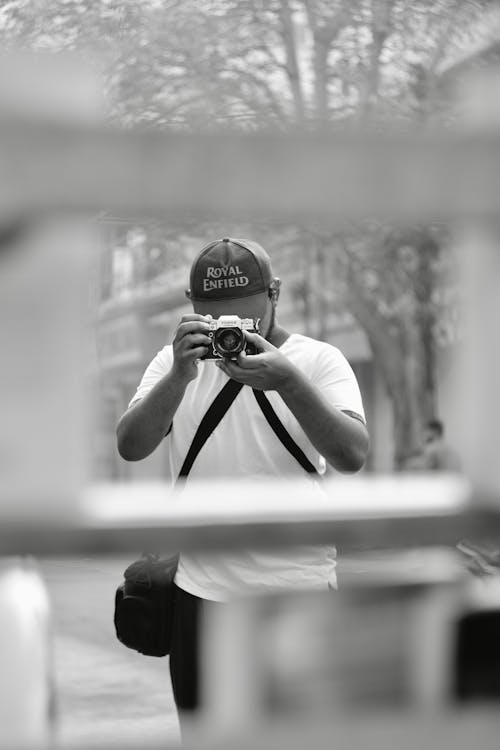 Black and White Photo of a Man Taking Pictures with a Film Camera 