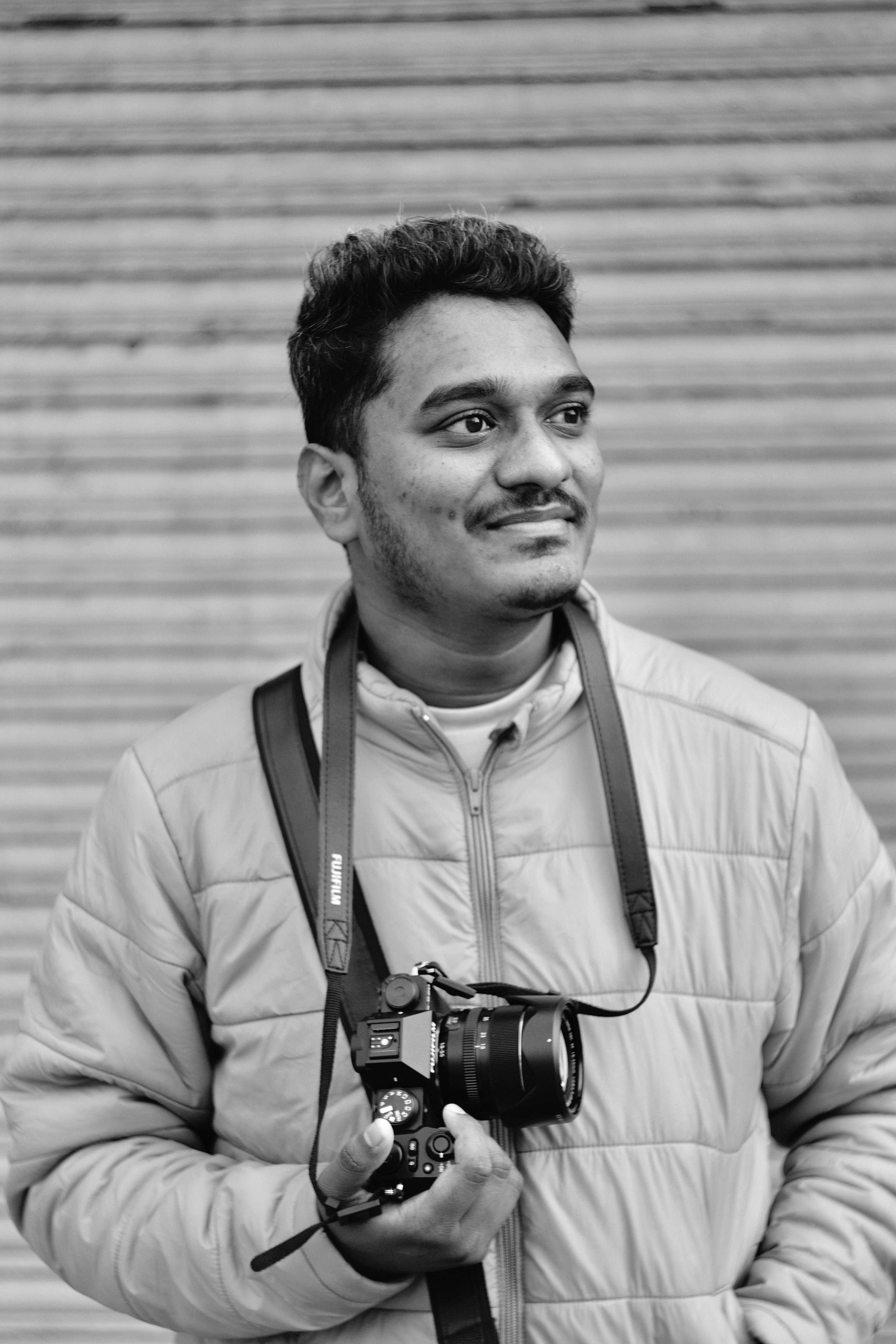Portrait of a smiling man with camera in black and white.