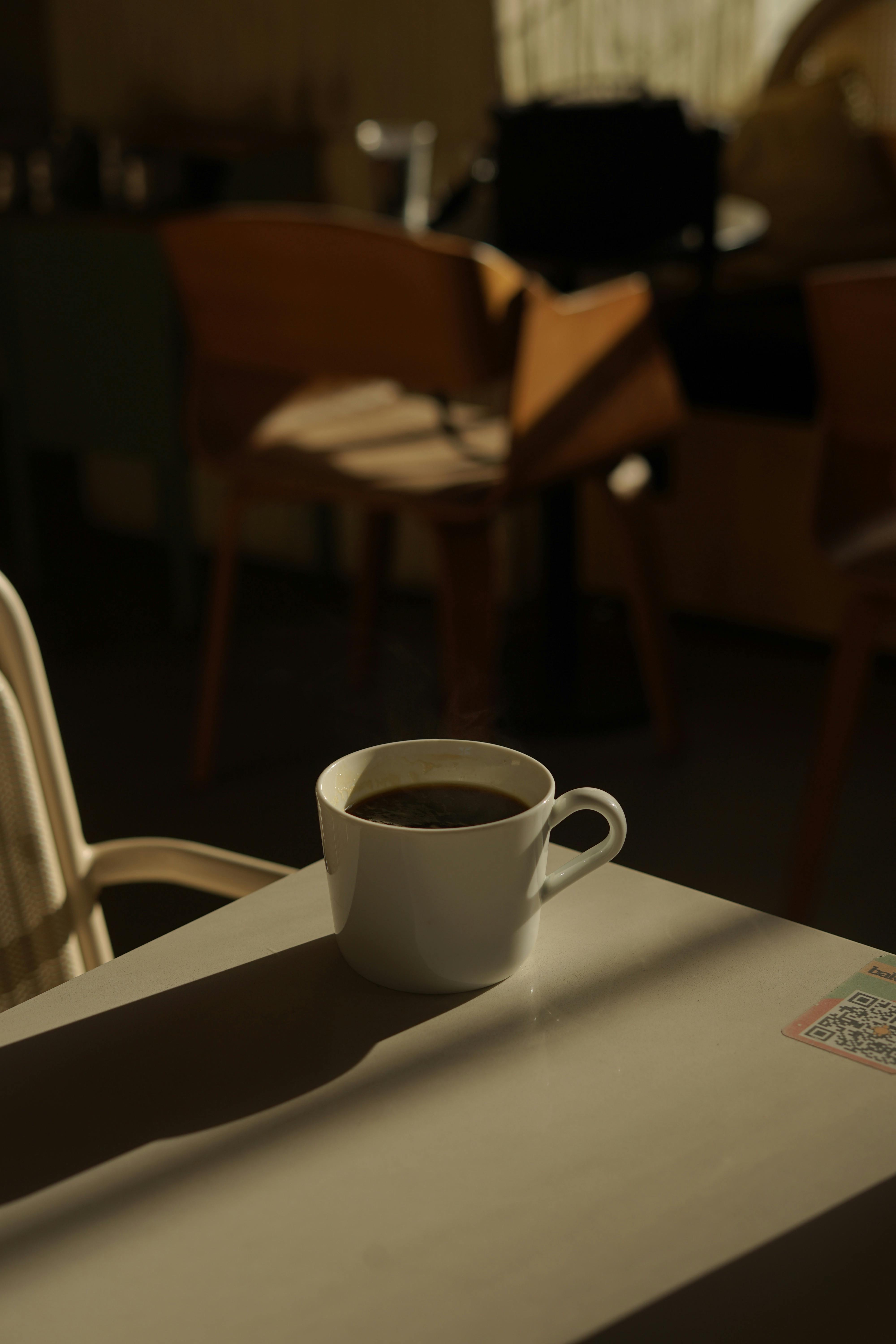 A coffee cup on a café table with warm sunlight and shadows. Captured in Samsun, Türkiye.