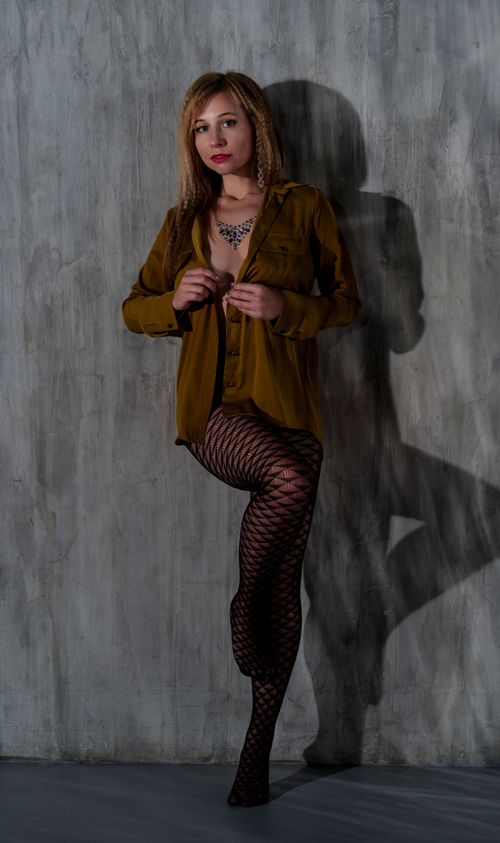 Free Model posing against textured wall wearing blouse and stockings in a modern fashion photo. Stock Photo