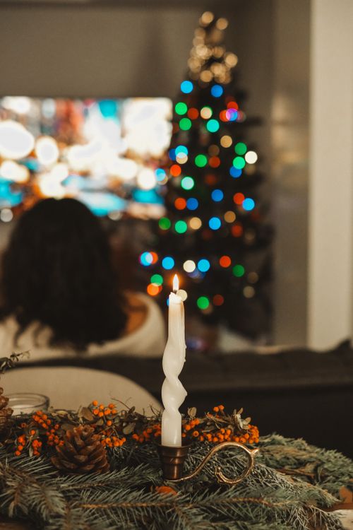 Free Warm holiday scene featuring a candle and a festive Christmas tree with lights. Stock Photo