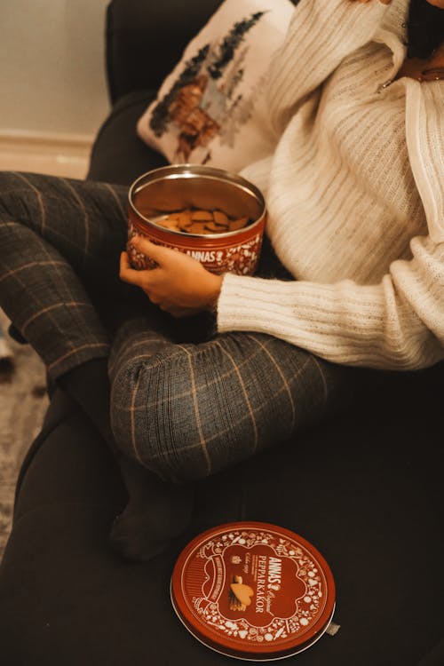 Woman in White Sweater and Gray Checked Pants Holding a Box of Ginger Cookies