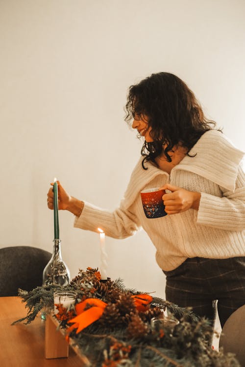 Woman Lighting a Candle at a Table Decorated for Christmas