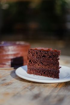 A rich chocolate cake slice on a rustic wooden table, perfect for dessert lovers.