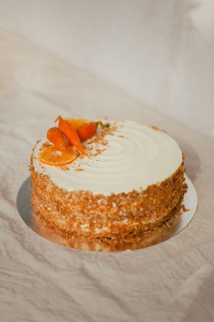 A mouthwatering orange cream cake topped with fresh fruit and nuts, perfect for dessert lovers.