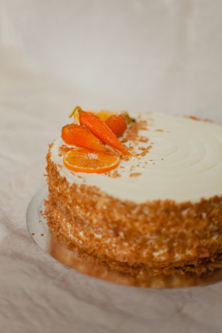 Close-up of a gourmet cake topped with fresh orange slices and crafted cream icing, perfect for dessert lovers.