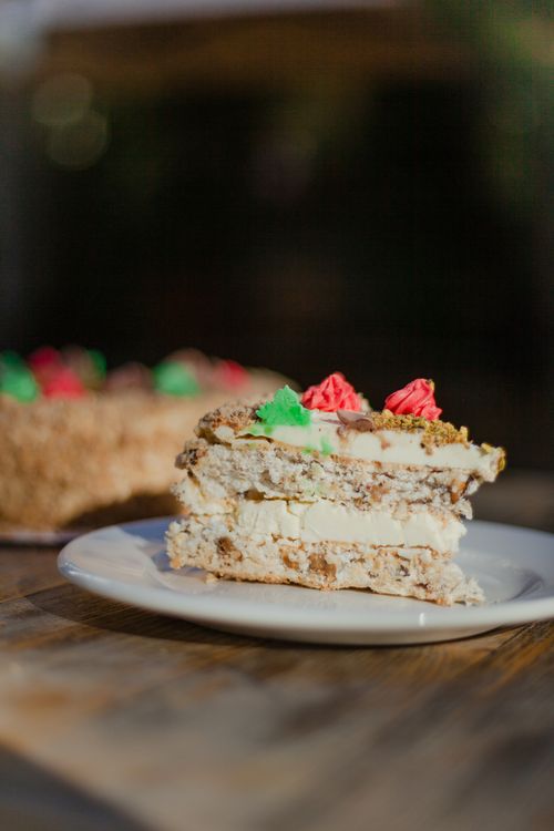 Free Close-up of a layered cake slice with cream frosting and colorful icing decorations on a plate. Stock Photo