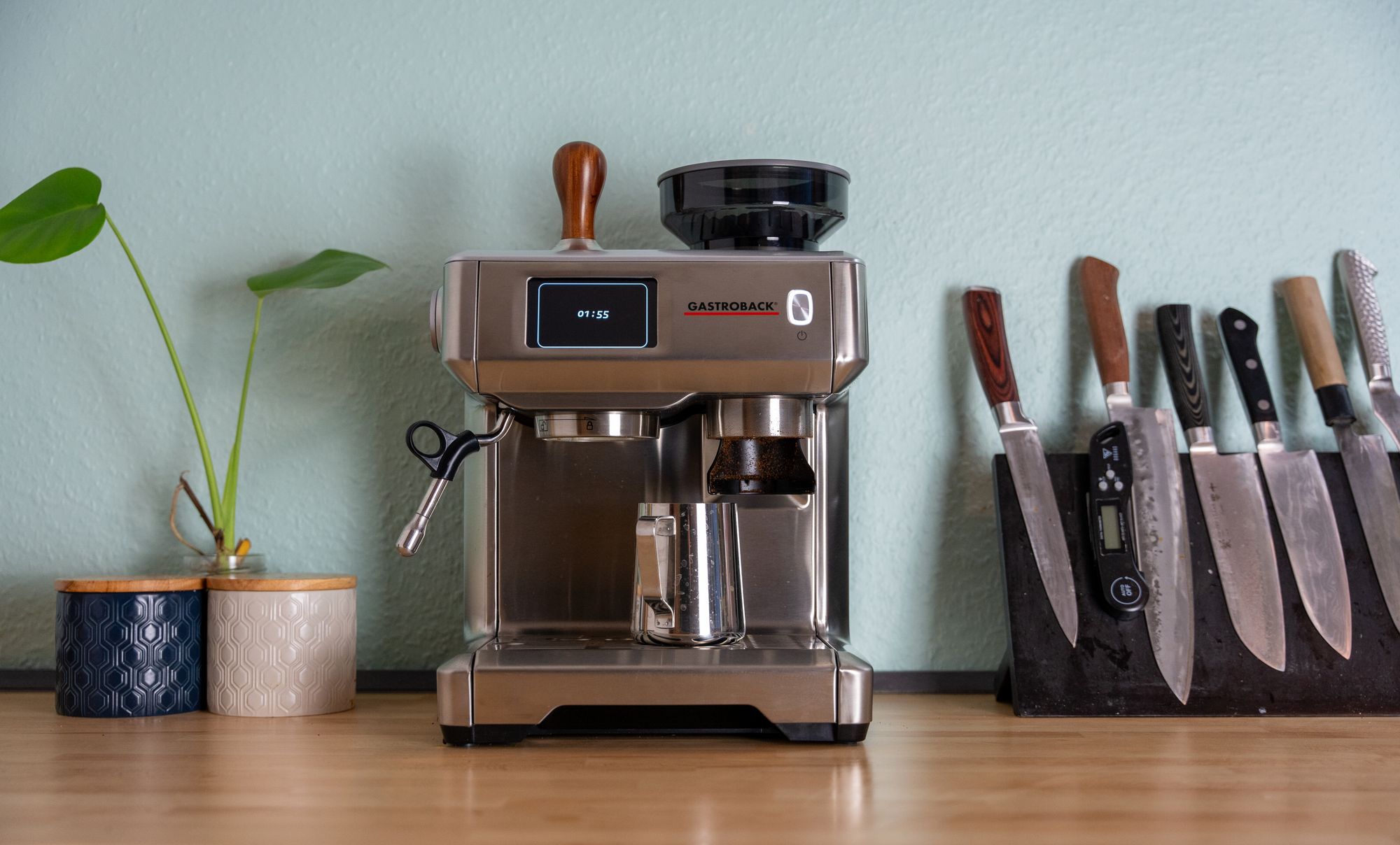 A countertop espresso machine arranged with cups and kitchen tools in a clean home kitchen