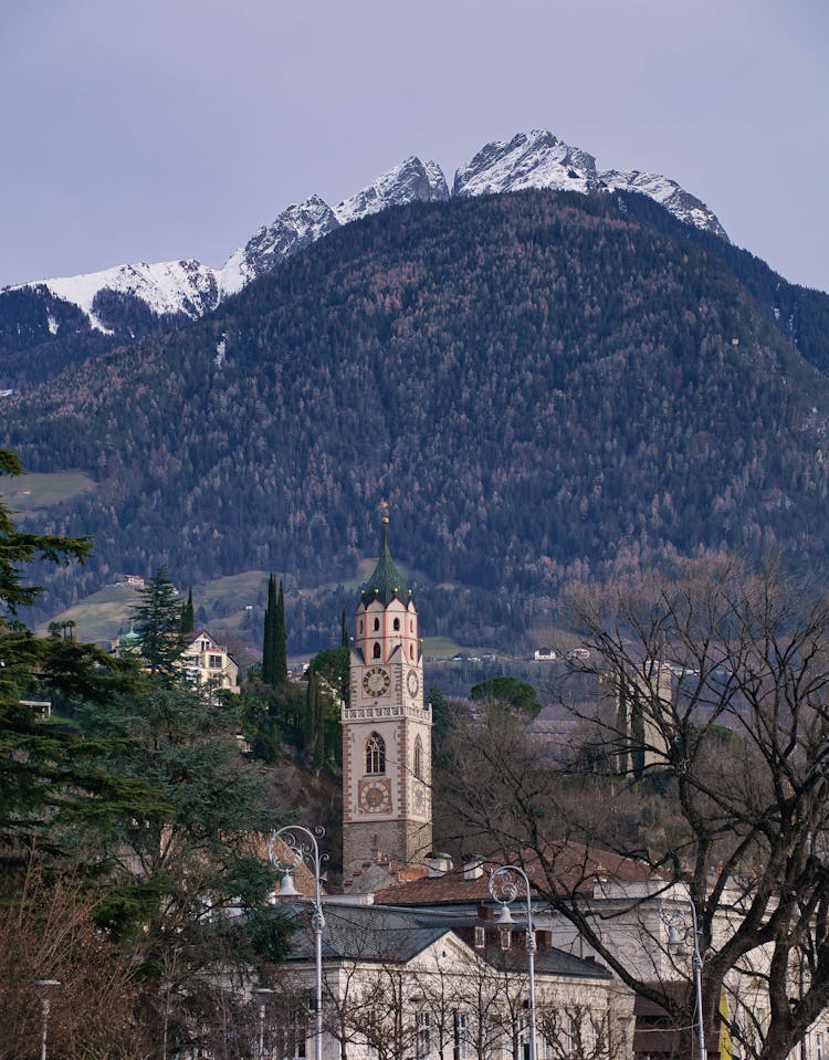 View Of The Tower Of St. Nicholas Church And Mountain In Merano, South Tyrol, Italy 