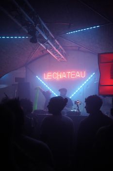 Vibrant nightclub scene at Le Chateau with DJ and dancing crowd under neon lights.