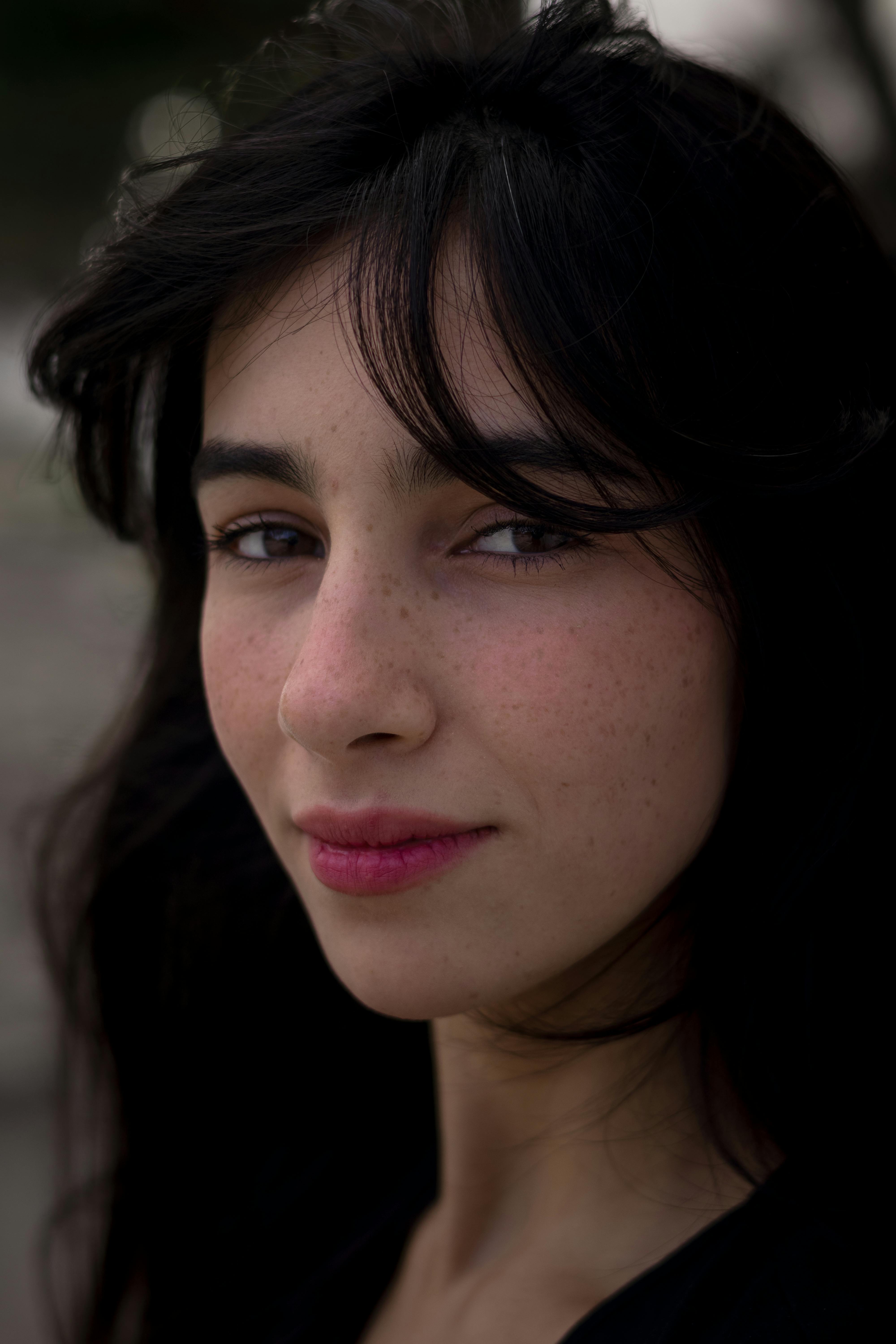 Close-up portrait of a woman with dark hair, looking confidently at the camera.