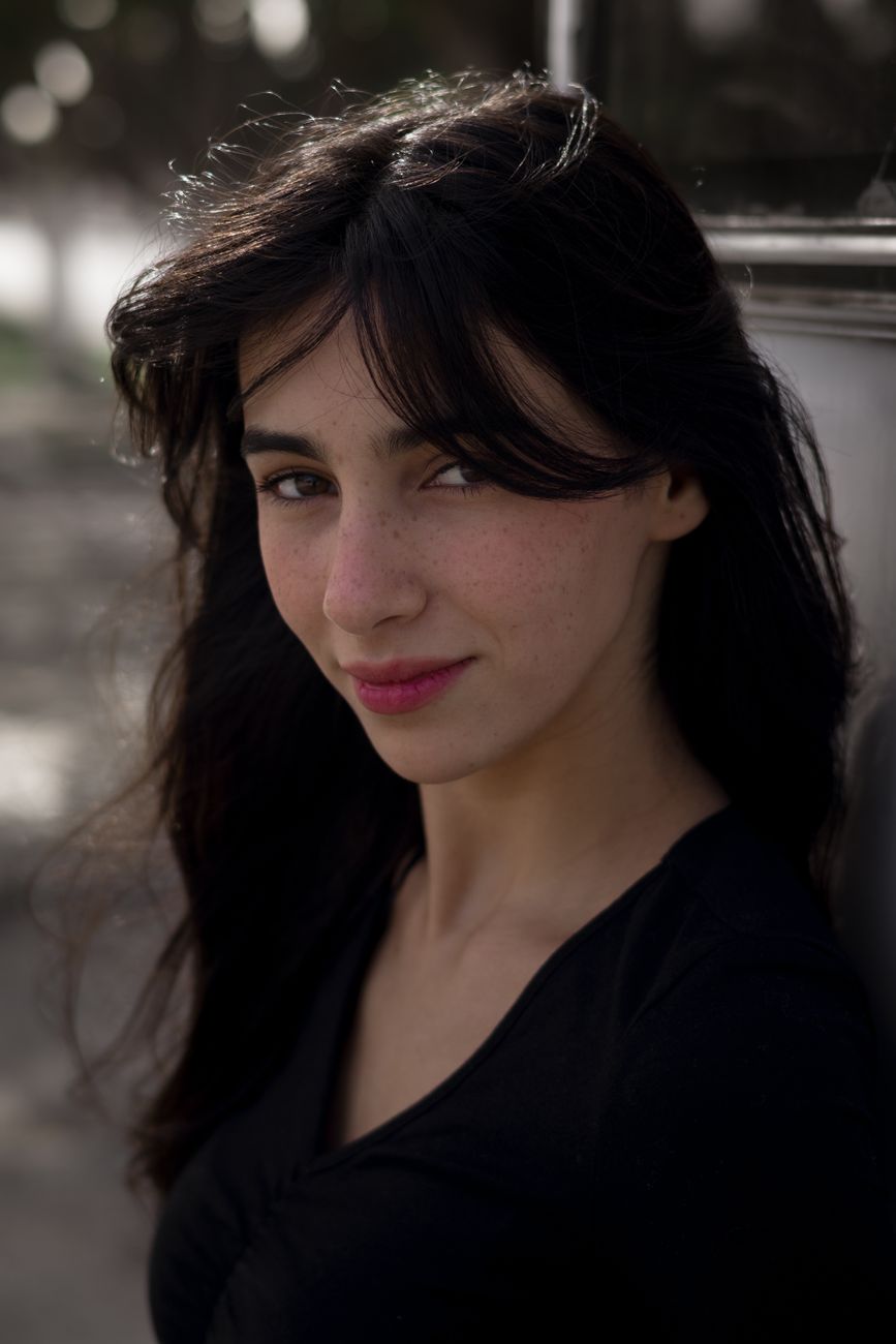 A captivating portrait of a young woman with long hair posing outdoors, exuding confidence and grace.