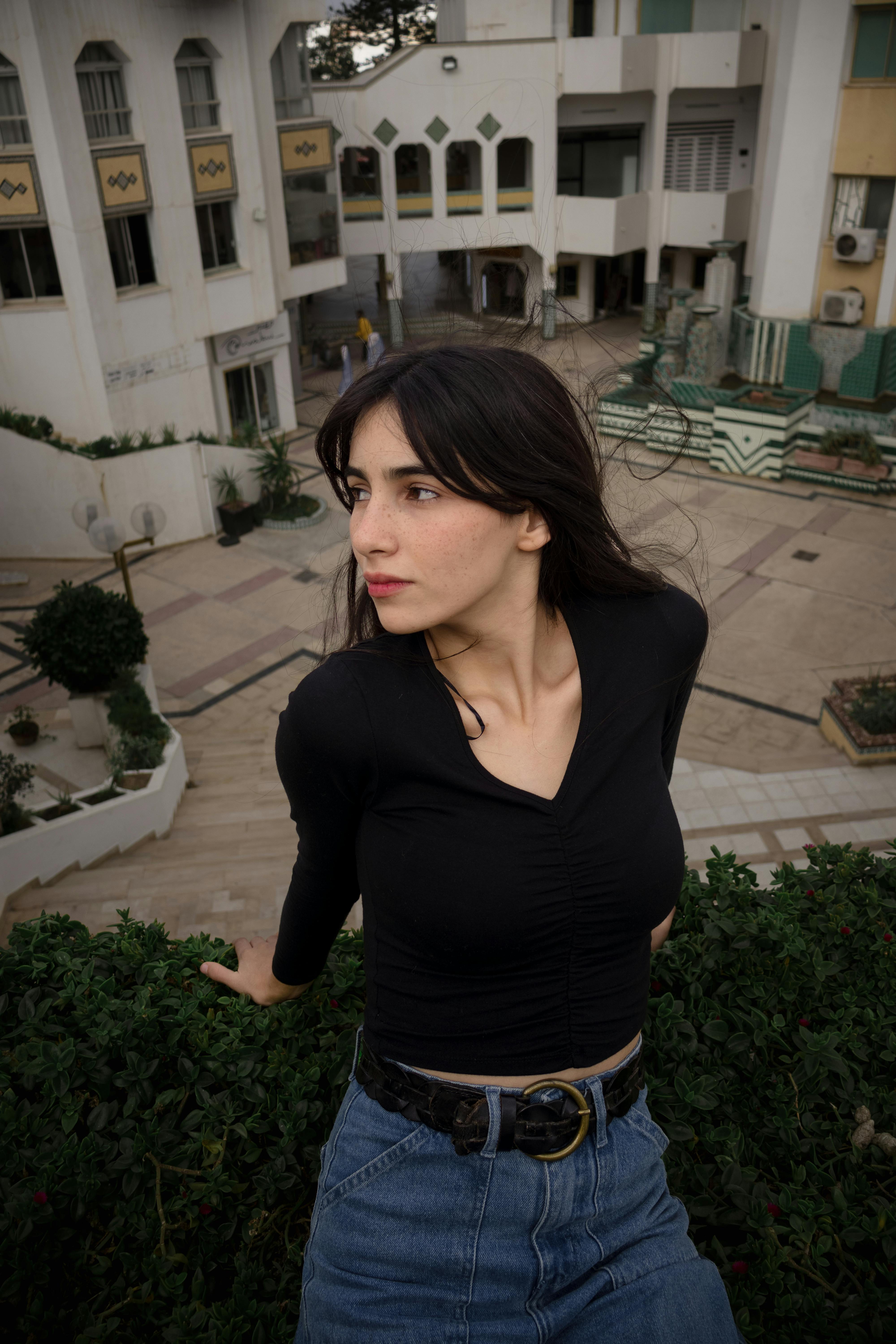 Free Portrait of a young woman in a modern urban environment showcasing fashion and architecture. Stock Photo