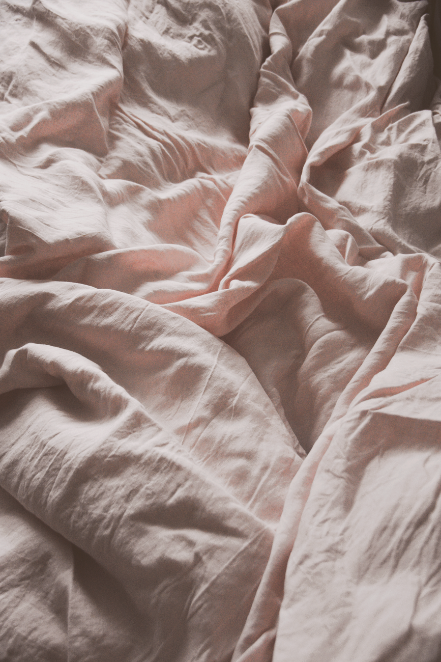 soft pink sheets crumpled into folds, close enough to show the texture