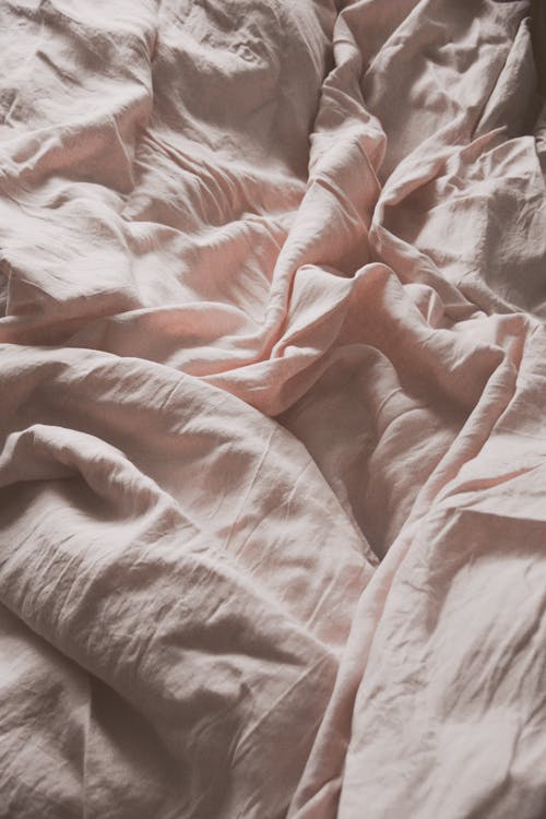 A bed with pink sheets and a blanket · Free Stock Photo