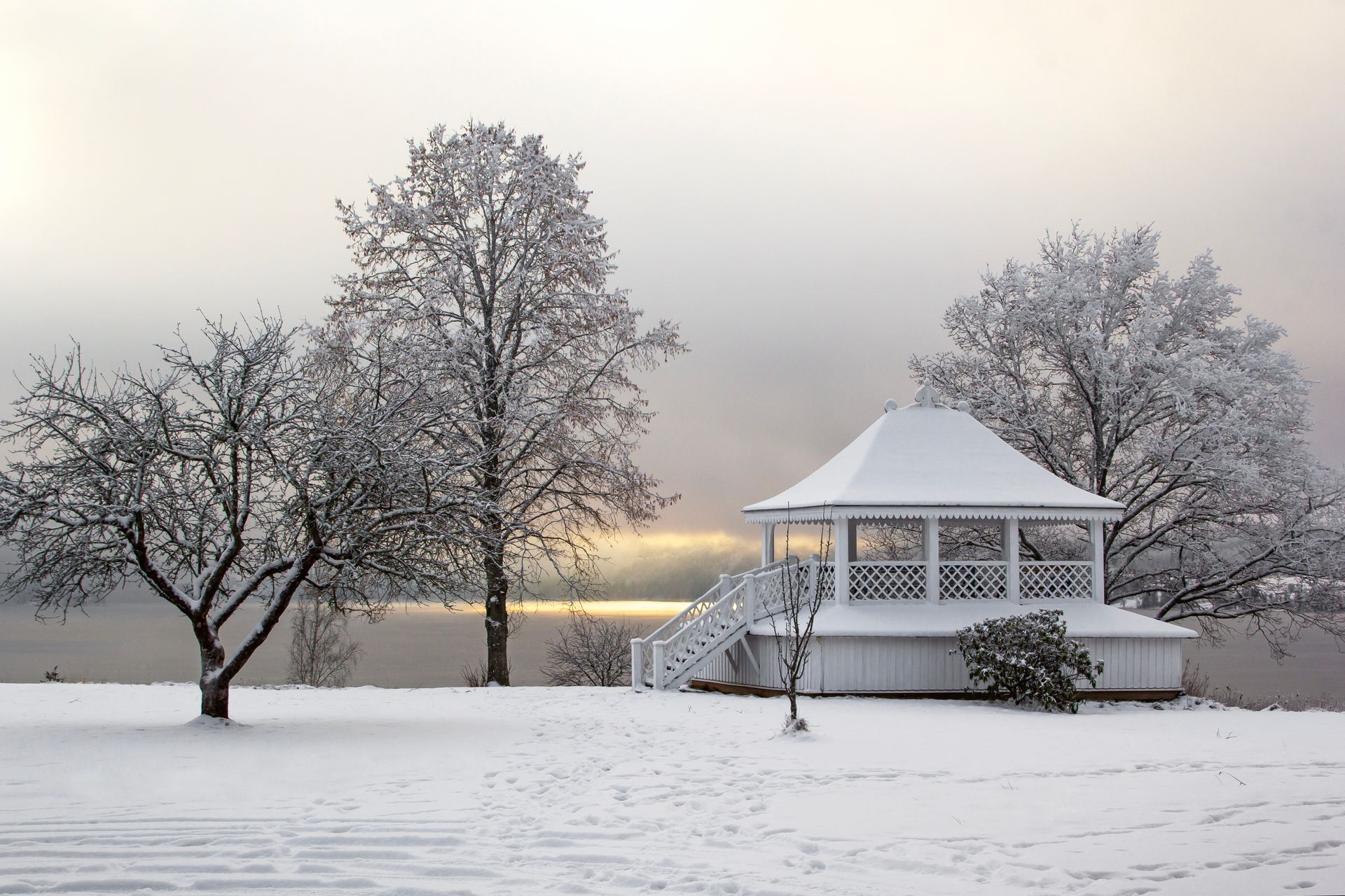 A Gazebo and Trees Covered in Snow in a Park by the Water