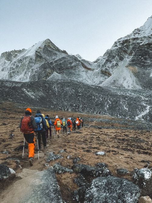 Free Group of trekkers hiking in Nepal's Himalayas with snow-capped peaks. Stock Photo